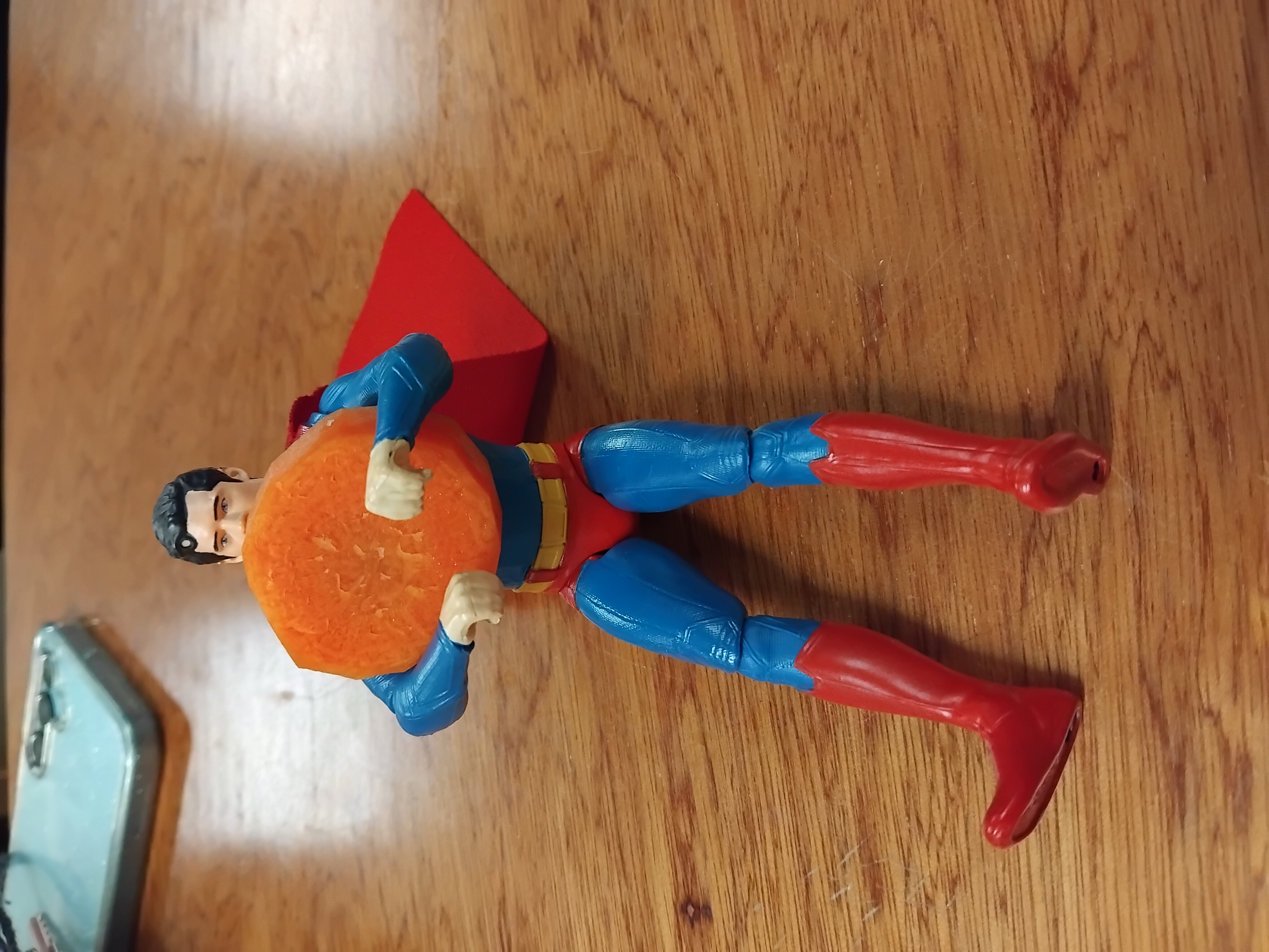 superman toy eating his vegetables (a carrot)